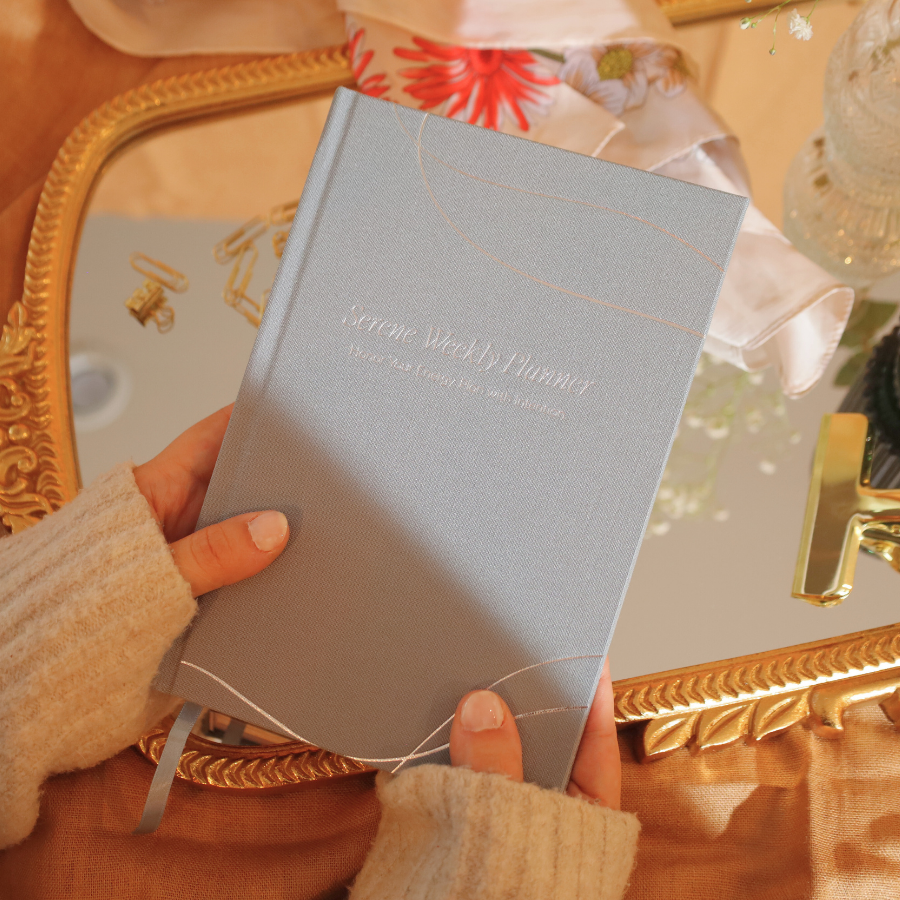 Hand holding a light blue notebook with decorative elements in the background