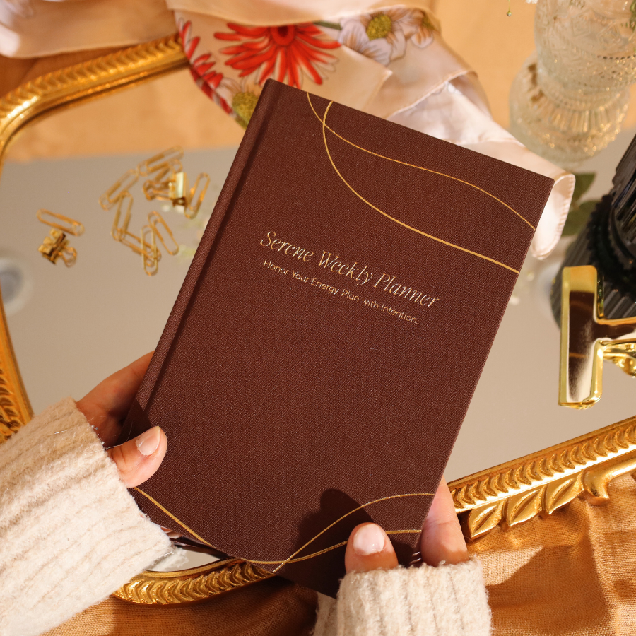 Brown planner held by a person with decorative background