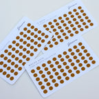 Three sheets of gold polka dot stickers on a white background