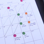 Calendar with colorful dots marking events, next to a pen.