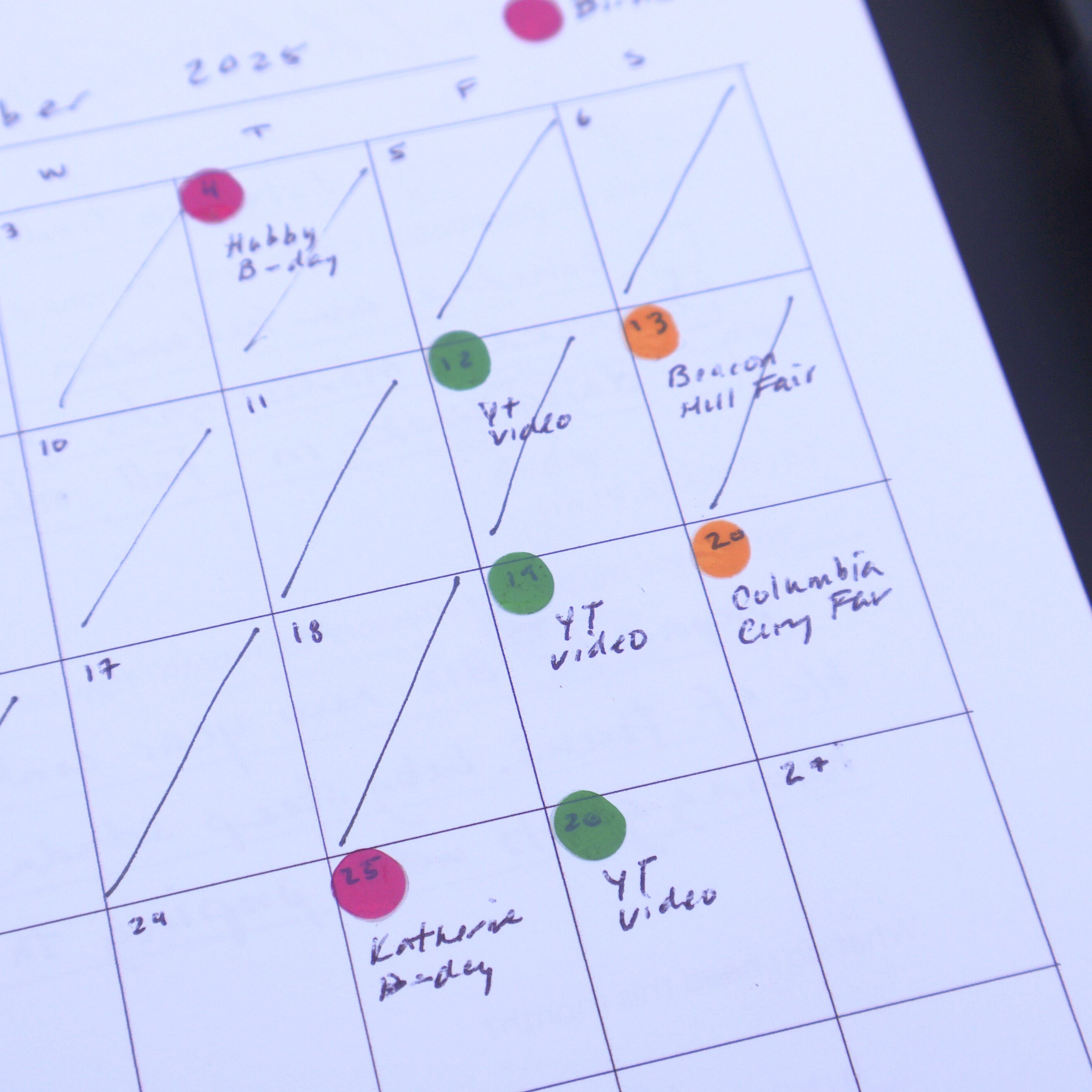 Calendar with colorful dots marking events, next to a pen.