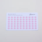 Sheet of pink dot stickers on a light gray background