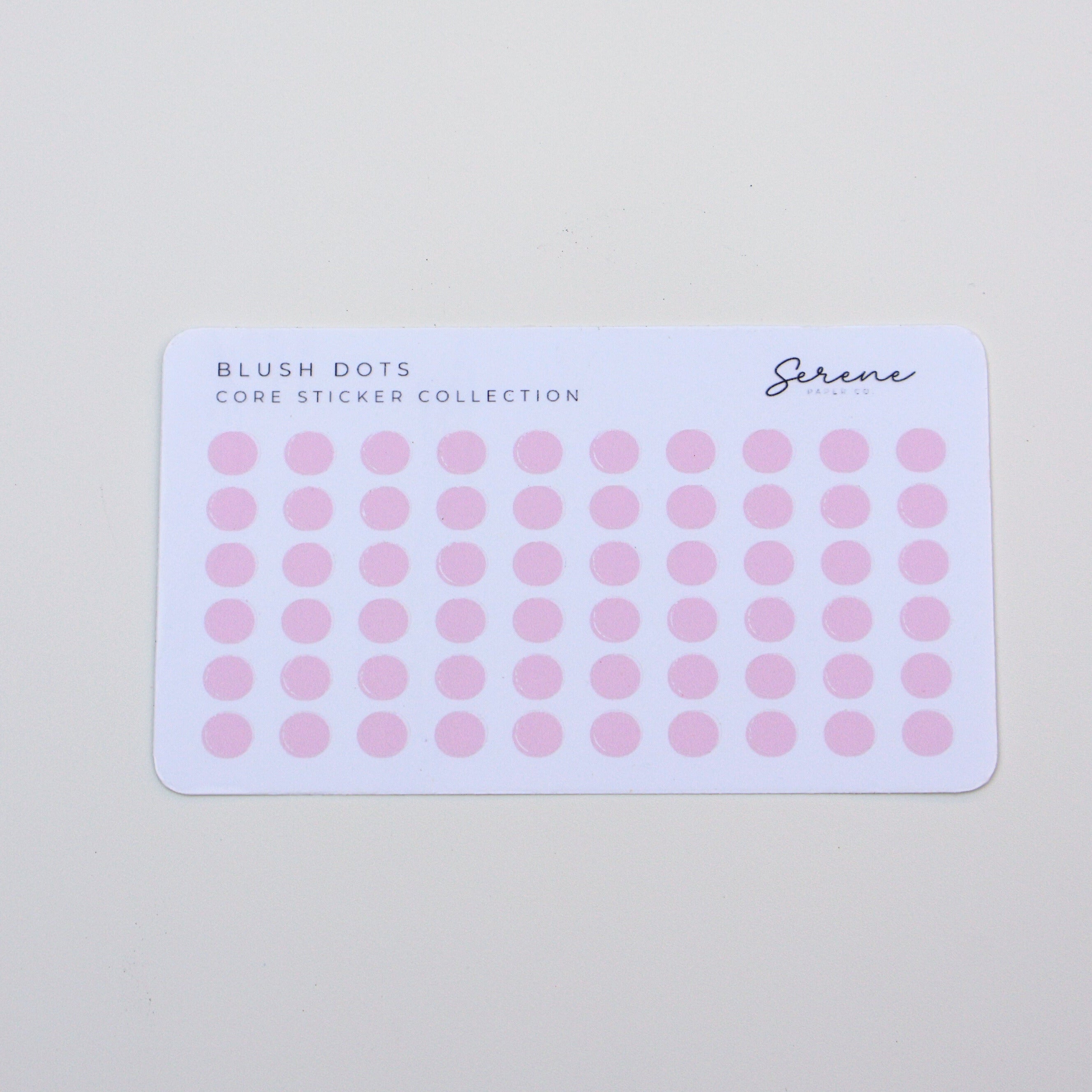 Sheet of pink dot stickers on a light gray background
