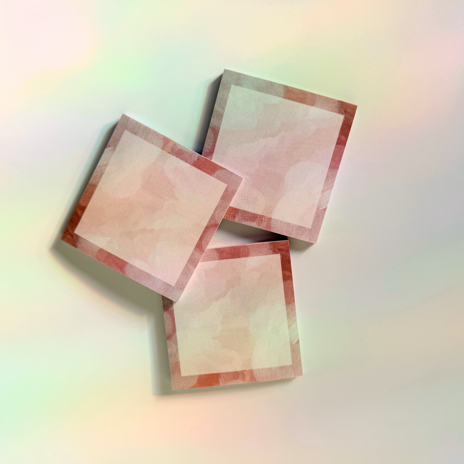 Three sticky note pads that are a couple shades of pink 