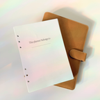 White planner with text and brown cover on a gradient background