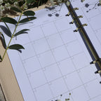 Planner monthly calendar close up shot. has florals surrounding it. 
