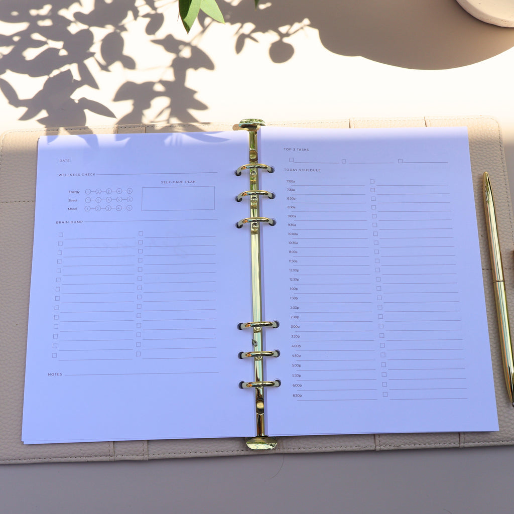 Open planner with blue pages on a light surface, with a pen and decorative item in the background.