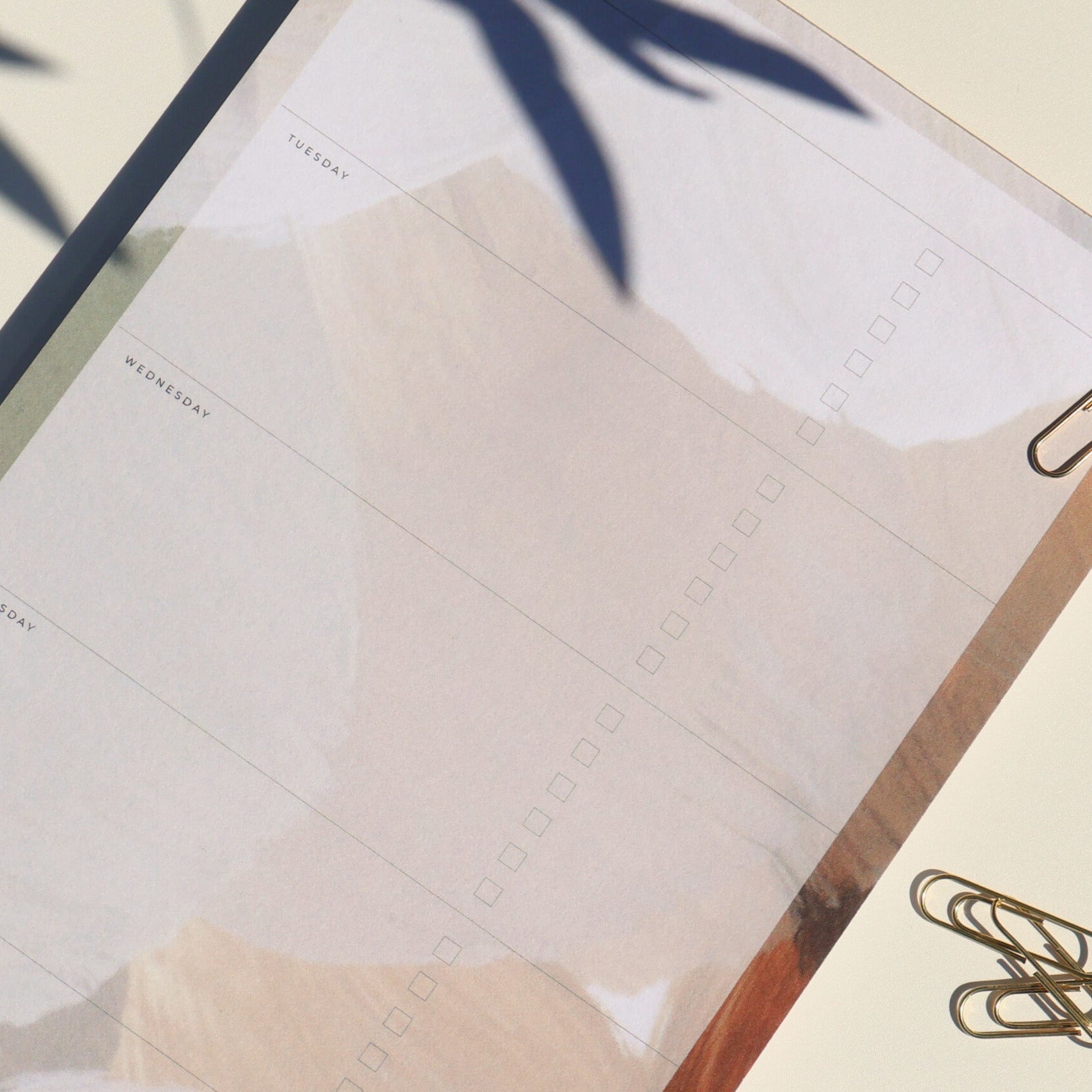 Close-up of a planner with a pink cover and gold clip on a light background