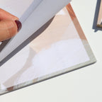 Hand holding a notepad on a light surface.