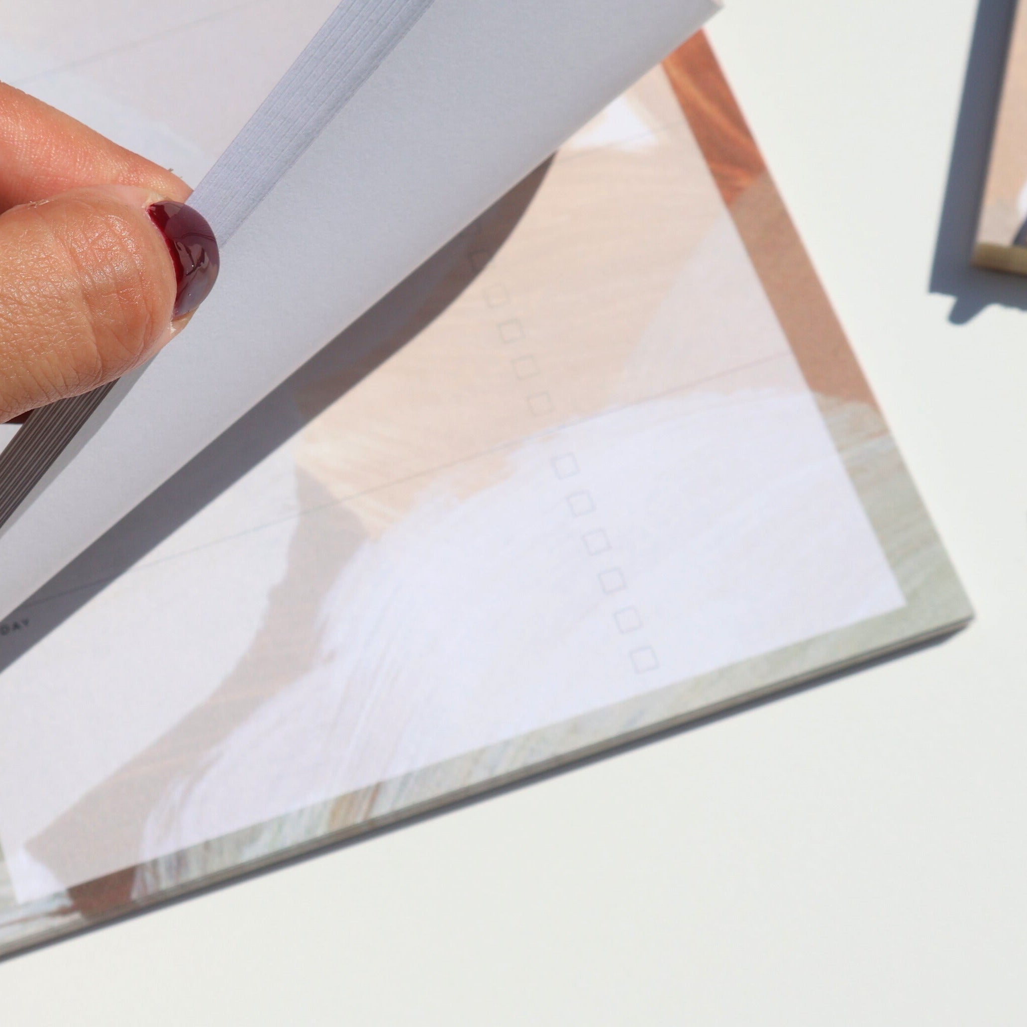 Hand holding a notepad on a light surface.