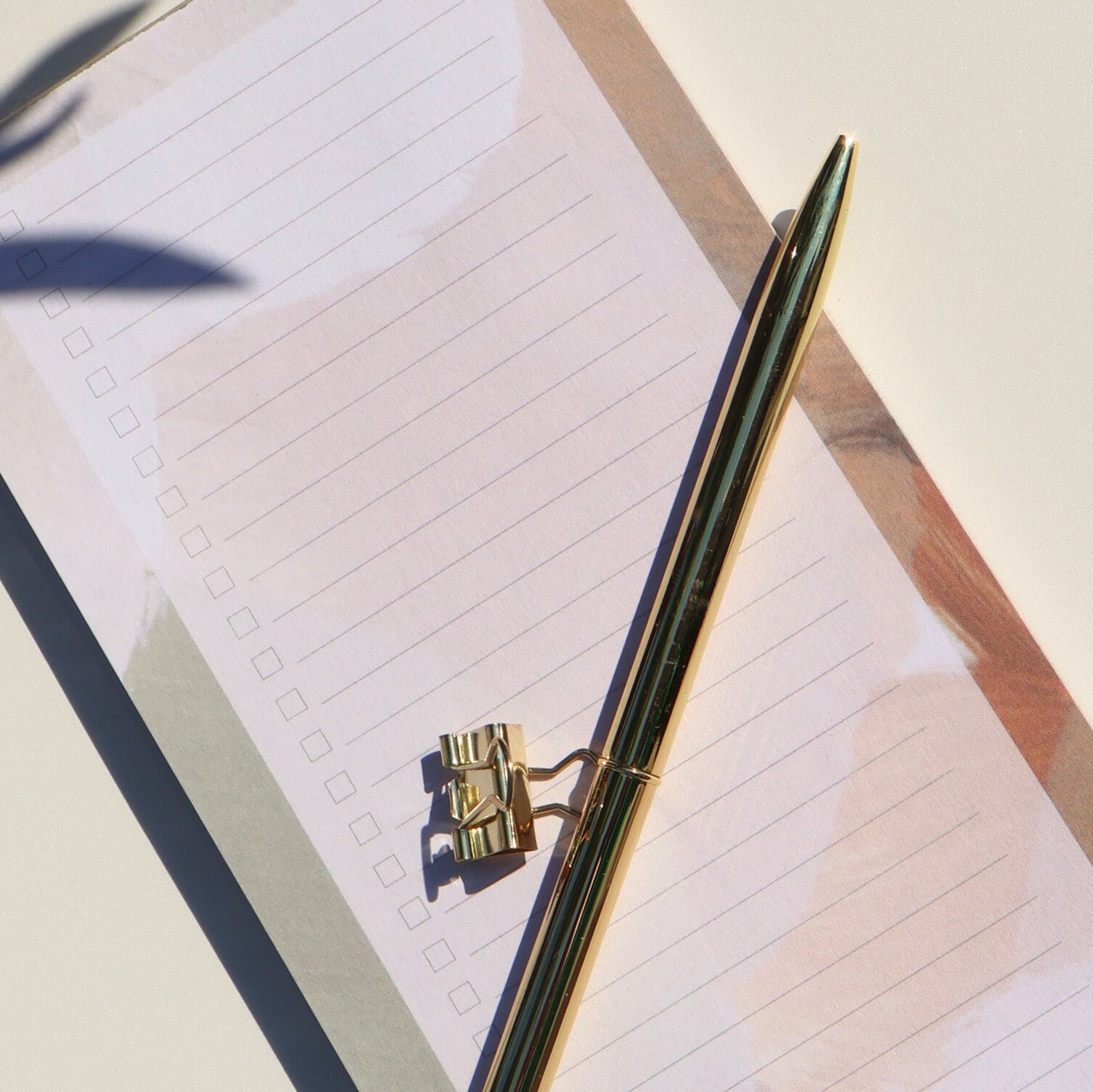 Pen and notebook on a light surface with shadows