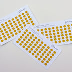 Four sheets of yellow dot stickers on a light gray background
