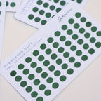 Green dot stickers on white cards with 'Serene Paper Co' branding on a light background