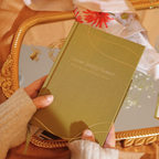 Hand holding a green planner with decorative elements in the background