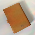 Brown leather notebook with 'Saint Vito' branding on a reflective surface