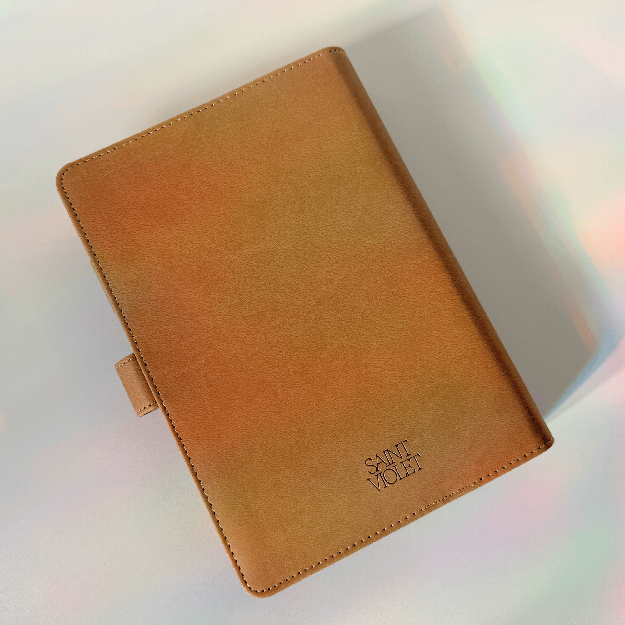 Brown leather notebook with 'Saint Vito' branding on a reflective surface