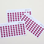 Three sheets of red dot stickers on a light gray background