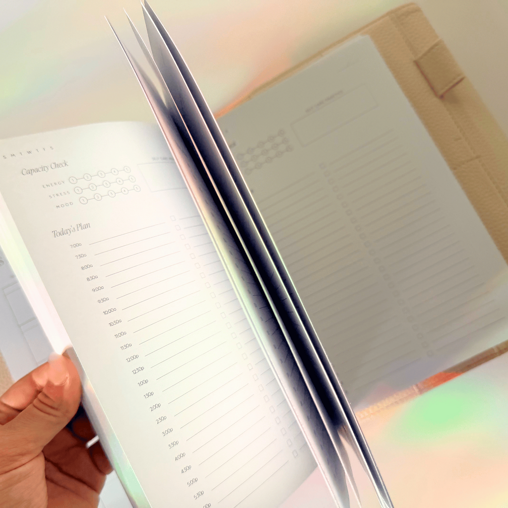 Hand holding a planner with a rainbow light effect