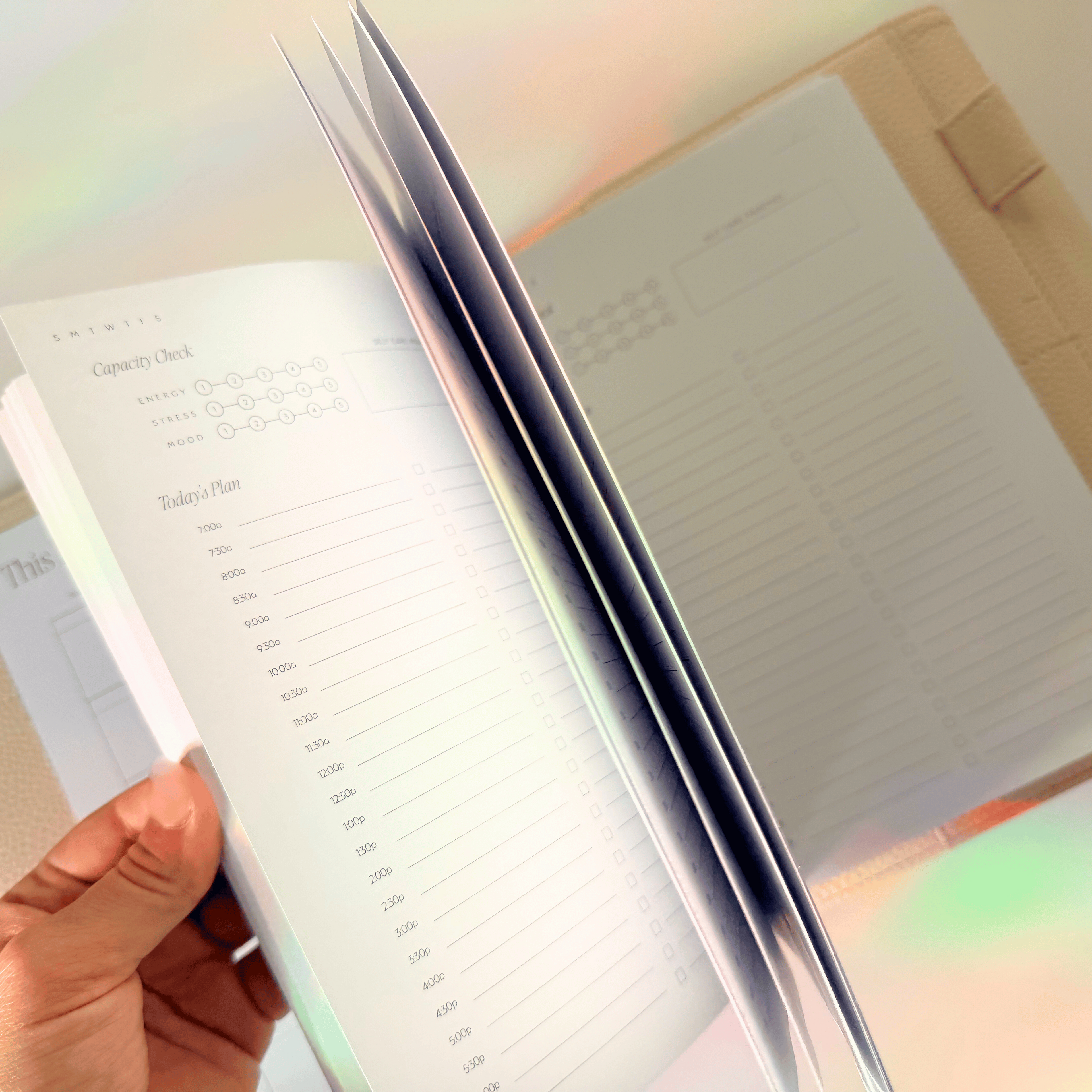 Hand holding a planner with a rainbow light effect
